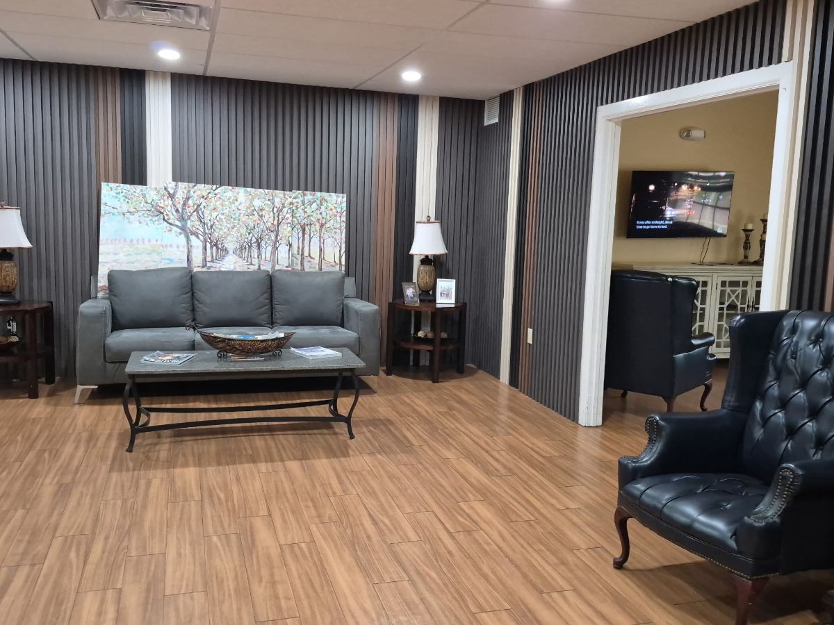 The front lounge at KIVA at Canterbury, with a sofa, coffee table and a painting of a tree-lined path