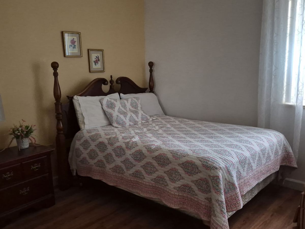 A private resident suite at KIVA at Canterbury with a wooden bed, dresser and fresh flowers