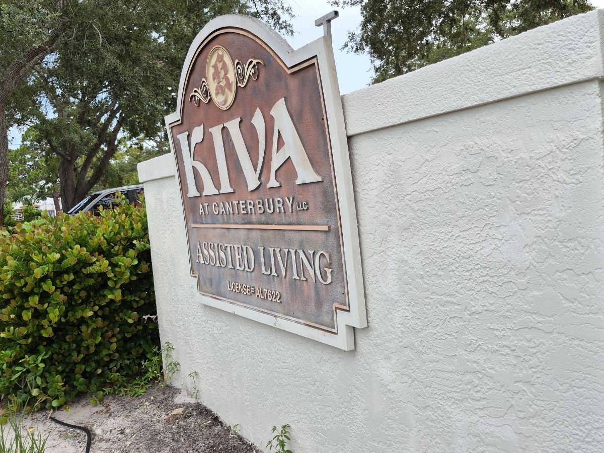 The KIVA at Canterbury assisted living sign, mounted on the white garden wall at the entrance on 7th Street